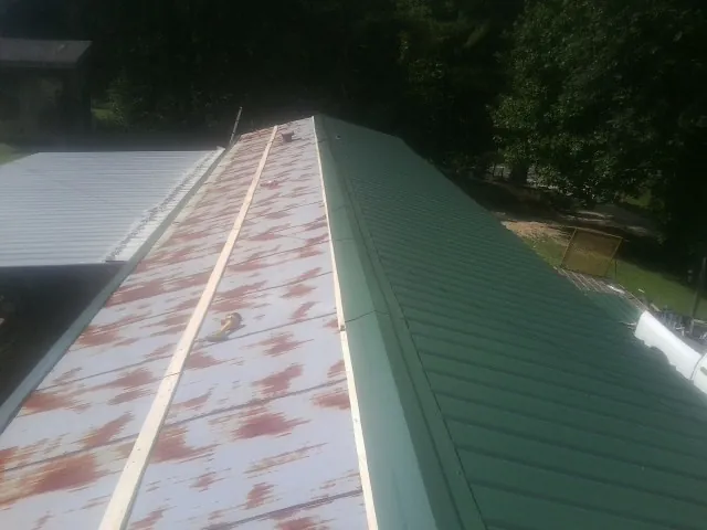 Old rusted panels beside newly installed green metal roofing — Wind Damage Roof Repair by Roofing Brothers in Altoona