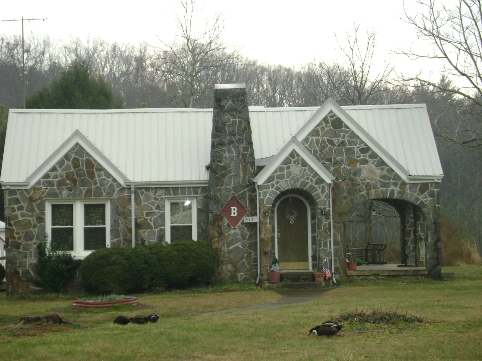 White metal roof on a stone cottage with steep gables in Altoona