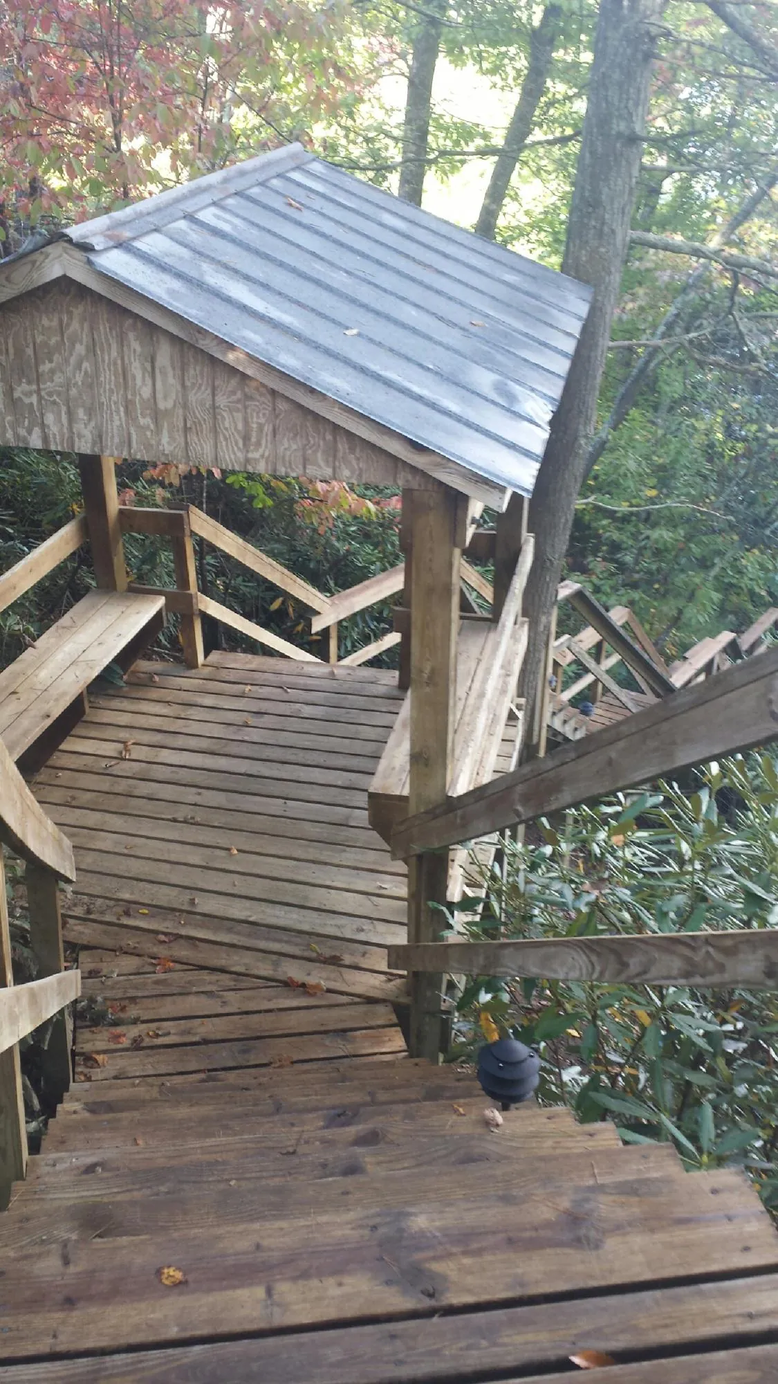 Metal roofed shelter over wooden steps on a wooded walkway — Skylight Repair & Installation work by our crew in Altoona